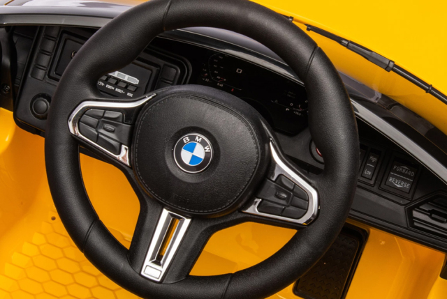 Gul BMW M4 Competition elbil ti l børn med lædersæde, 2x12V motorer, EVA-gummihjul og musikanlæg.